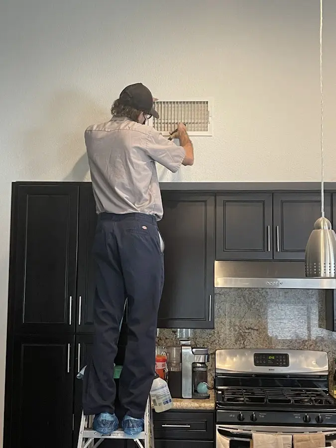 Technician inspecting an air vent during HVAC service in Summit